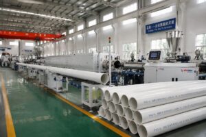 A full plastic extrusion production line running finished PVC pipe products on a factory floor